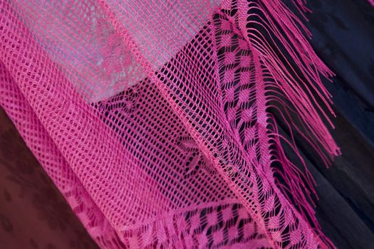 A pink lace shawl on a dark background.