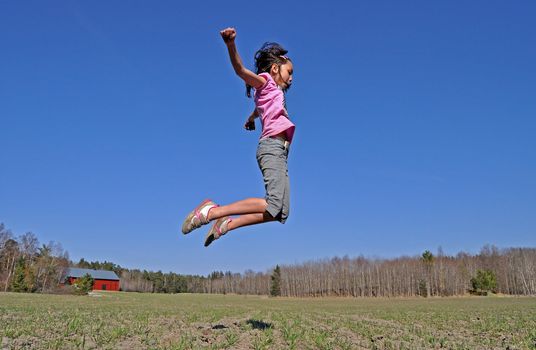 A young girl jumps in the countryside, happy that the spring finally has arrived.