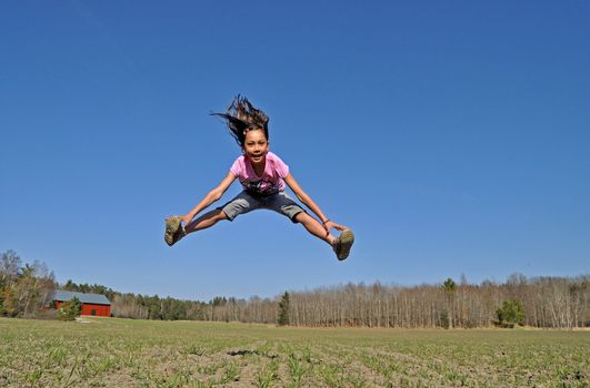 A young girl jumps in the countryside, happy that the spring finally has arrived.