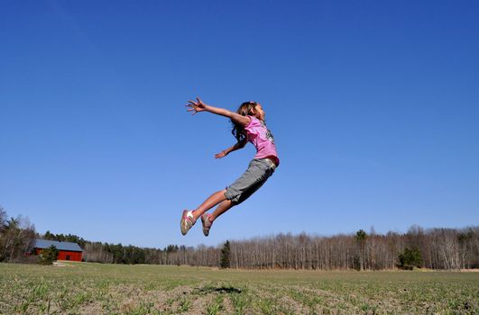 A young girl jumps in the countryside, happy that the spring finally has arrived.