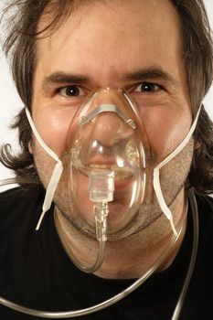 A male breathing through an oxygen mask with odd expression on his face.
