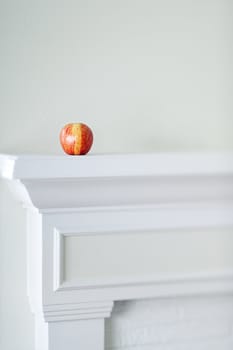 A red apple on a fireplace mantle.