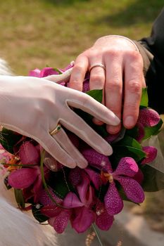 Newlywed couple holding hands over bouquet of flowers.