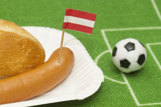 Sausage with roll on a football field background with soccer ball