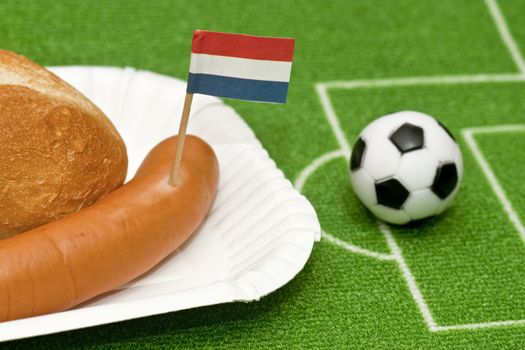 Sausage with roll on a football field background with soccer ball