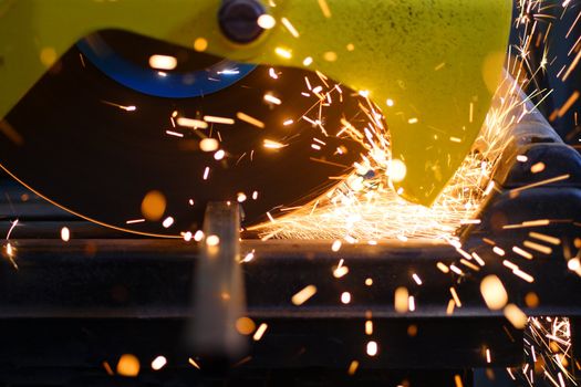 Closeup of a metal cutting saw slicing through a steel pipe.
