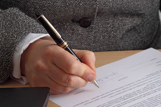 Hand with pen and contract. Shot in studio.
