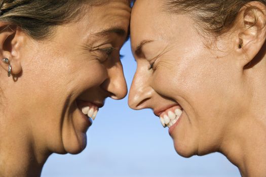 Caucasian mid-adult women with their heads together smiling.