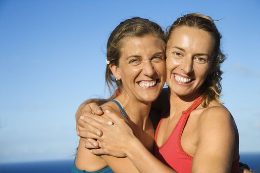 Caucasian mid-adult women hugging each other smiling.