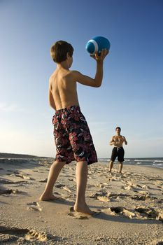 Caucasian pre-teen boy throwing football to mid-adult male.