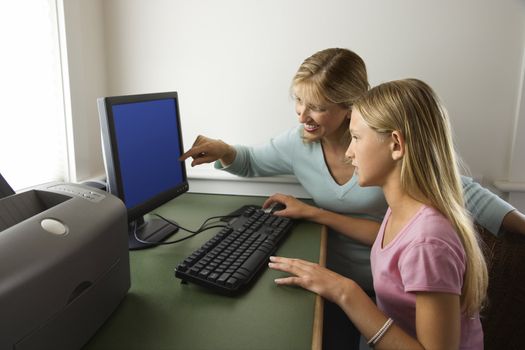 Caucasian pre-teen girl and Caucasian prime mid-adult woman working on computer together.