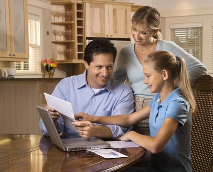 Caucasian family paying bills on laptop computer.