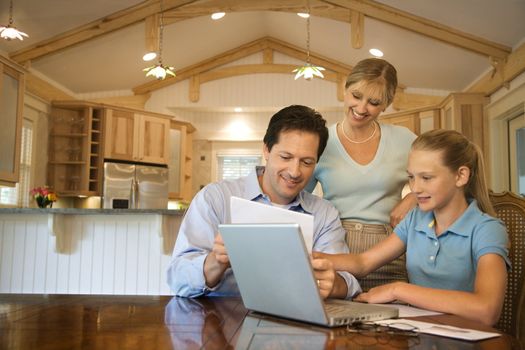 Caucasian family paying bills on laptop computer.