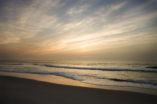 Ocean waves lapping on the shore at sunset.