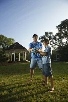 Caucasian mid-adult man teaching football to Caucasian pre-teen boy.