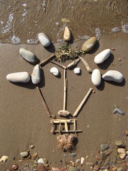 african mask drawed with pebbles on the beach