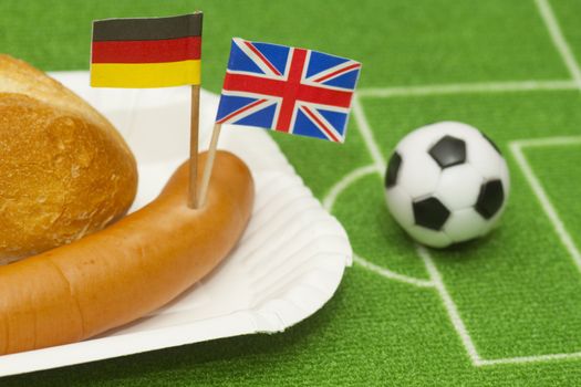 Sausage with roll on a football field background with soccer ball