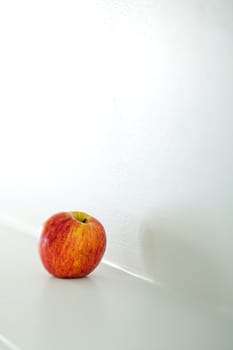 A red apple on a fireplace mantle.