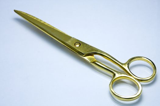 Modern goldl scissors on a blue background