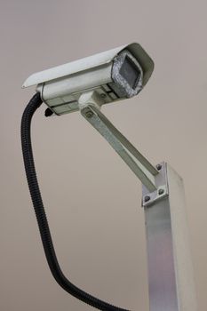 A security camera peers down from the corner of the building, watching your every move.