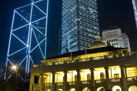 It is night scene of two skyscrapers behind a English building in Hong Kong