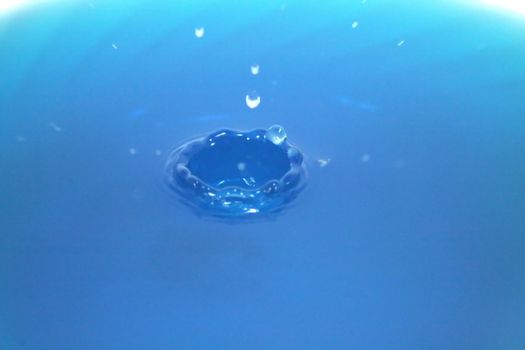 A crown of water rising out of a blue liquid.