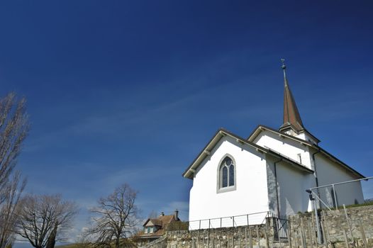 The church in the Swiss wine-growing village of Fechy. Space for copy in the clear blue sky.