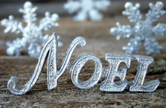 The words Noel on a piece of wood for a rustic look.  Snowflakes in the background for a look of winter.