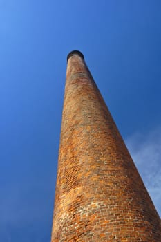 An old brick-built factory chimney against a blue sky.