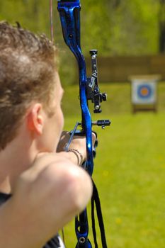 An archer aims at the bullseye of a distant target. Selective focus on the arrow in the bow.