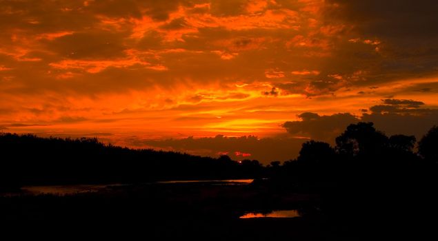 Burning and boiling sunset in a stormy sky over the Poudre river on the plains of Eastern Colorado