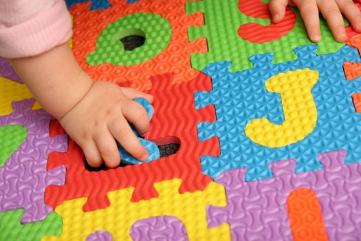 child playing multi colored alphabet puzzle