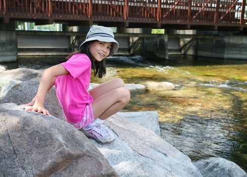 Little girl playing on rocks by river