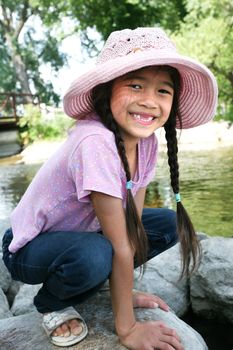 Little girl playing on rocks by river