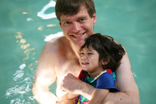 Father swimming with toddler in pool