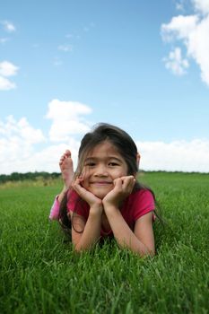 Little girl lying on grass in summer