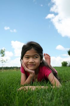 Little girl lying on grass in summer