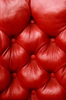 Background image of plush red leather from an antique seat.
