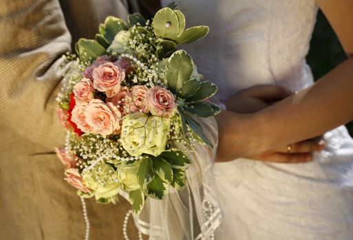Bouquet of flowers on a background of a dress of the bride and a suit the groom. 