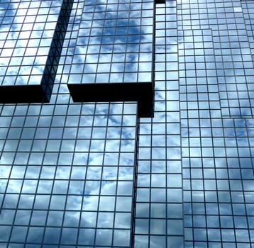 A building that has an interesting set of windows, with clouds reflected in the glass.