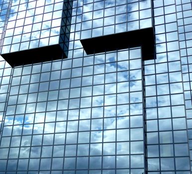 A building that has an interesting set of windows, with clouds reflected in the glass.