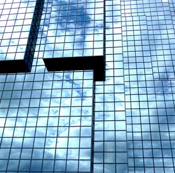 A building that has an interesting set of windows, with clouds reflected in the glass.