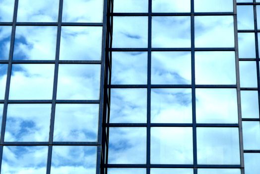A building that has an interesting set of windows, with clouds reflected in the glass.