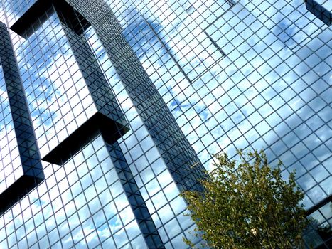 A building that has an interesting set of windows, with clouds reflected in the glass.