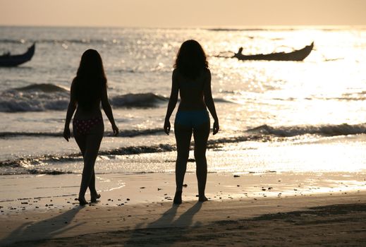 Two silhouettes of girls at coast of ocean