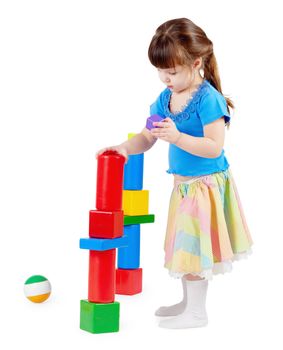 Girl build a tower of toy bricks on a white background