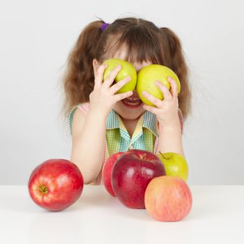 Funny child playing with two apples on table