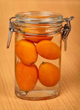 Kumquat is sealed in a small tin can on a wooden background