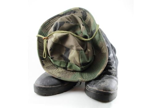 A camouflage hat resting on a pair of combat boots.