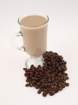 A hot cup of coffee sits amongst coffee beans. Isolated on a white background.